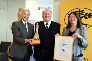 Prof. Dr. Claus Hipp steht zwischen Ulrike Höfken und Hans-Joachim Ritter und erhält den Ökologia-Preis 2017 mit Urkunde und Statue.
