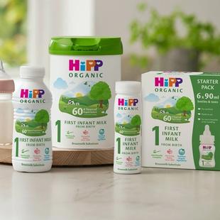 HiPP Organic First Infant Milk range, including powder tin, ready-made bottles and starter pack, arranged on a kitchen worktop