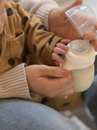 Mum preparing to bottle feed baby
