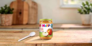 HiPP Bio Babygläschen Pfirsich in Apfel 190g auf Holztisch mit Löffel in heller Küchenumgebung