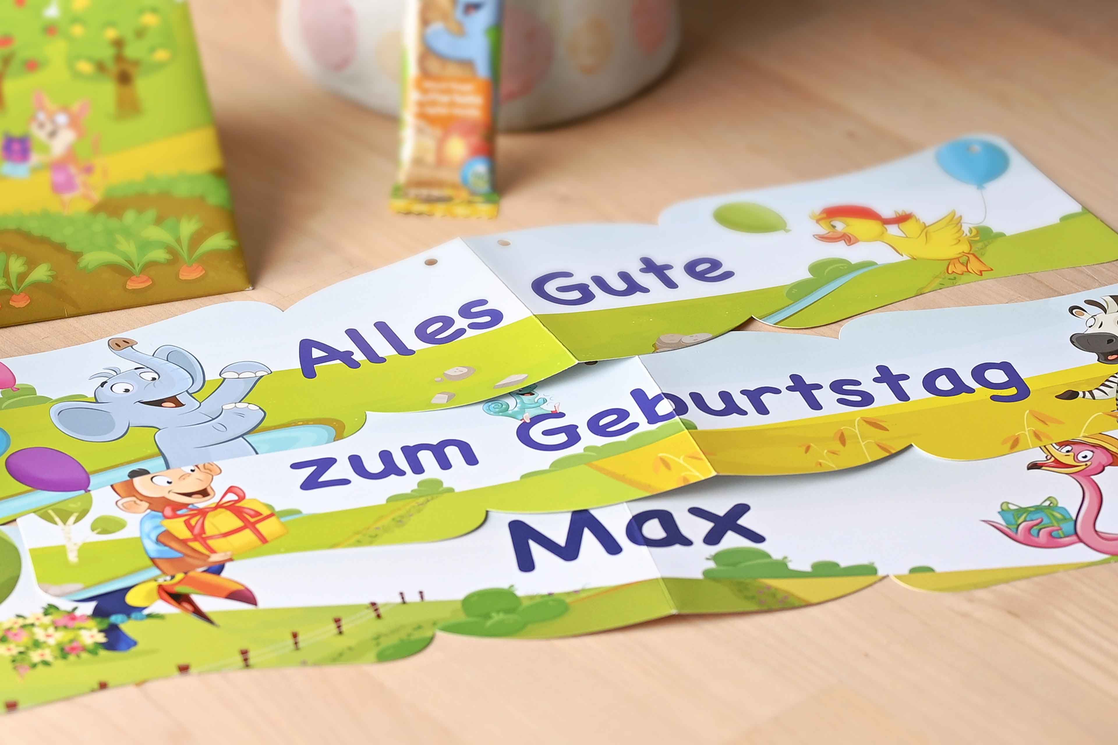 Bunte Girlande mit Tieren und dem Text 'Alles Gute zum Geburtstag Max' auf Holztisch