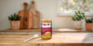 HiPP Glas Bulgur-Gemüsepfanne mit Kichererbsen und Bio-Rind auf Holztisch in heller, gemütlicher Küche mit Löffel daneben