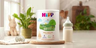 HiPP Organic anti reflux milk powder tin next to milk bottle on a kitchen worktop
