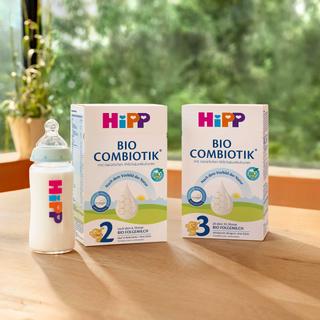 HiPP Babyflasche neben Packungen BIO COMBIOTIK® 2 und 3 auf einem Holztisch
