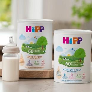 HiPP Organic Anti-Reflux and Comfort Milk tins on a kitchen worktop beside a prepared baby bottle of formula