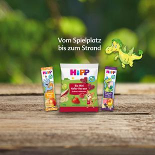 Drei Hipp-Produkte für Kinder mit der Aufschrift 'Vom Spielplatz bis zum Strand' und einer grünen Dinosaurierillustration