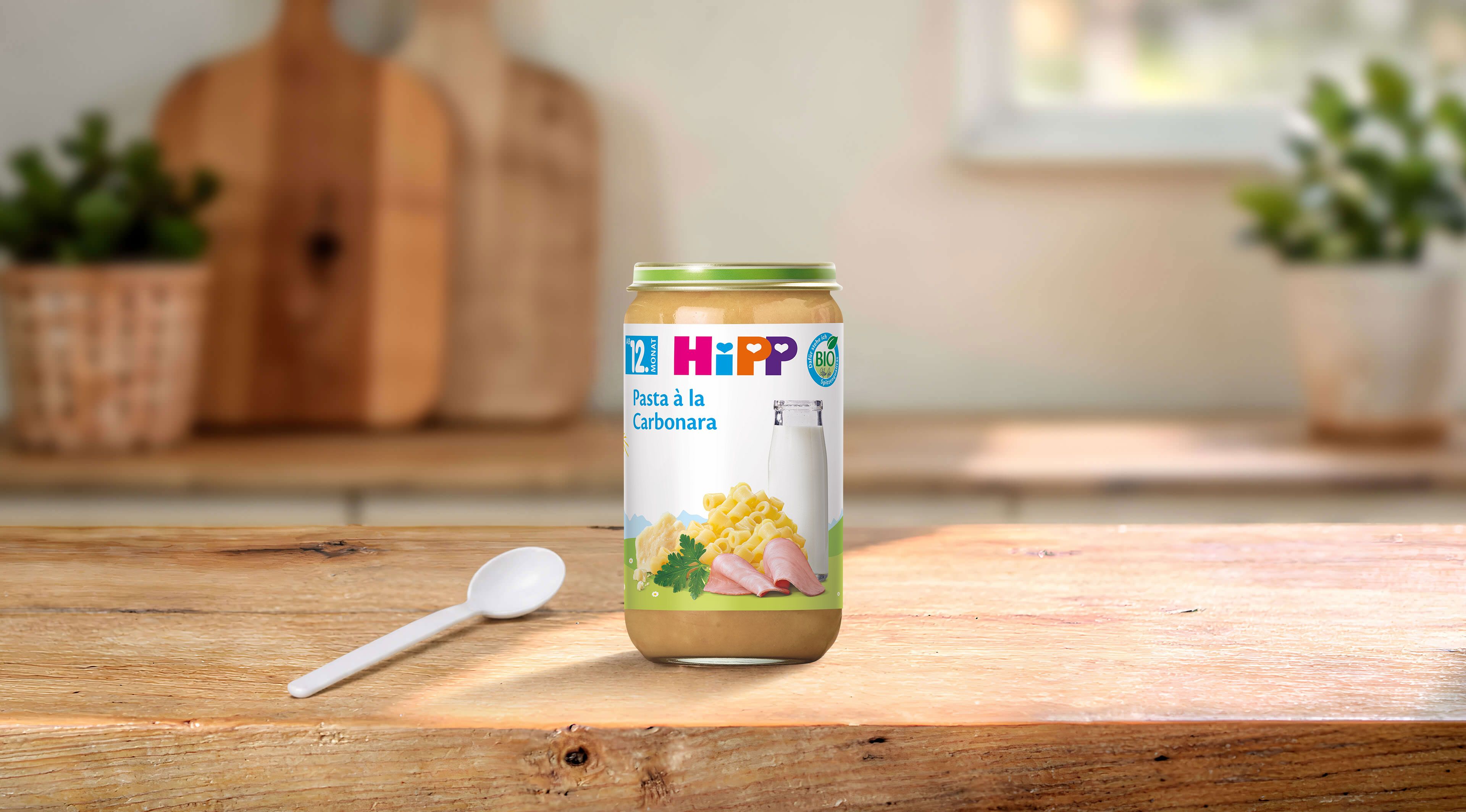 HiPP Bio Pasta à la Carbonara im 250-g-Glas mit Löffel auf einem Holztisch