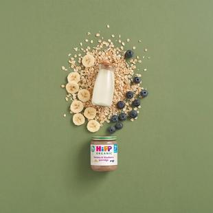HiPP Organic Banana & Blueberry Porridge jar with milk, oats, banana slices and blueberries on a green background