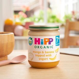 HiPP Organic Mango & Banana topped with Yogurt on a dining table next to a bowl and spoon