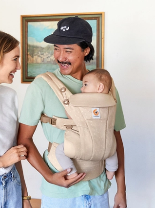 Dad wearing baby in ErgoBaby carrier whilst laughing with mum