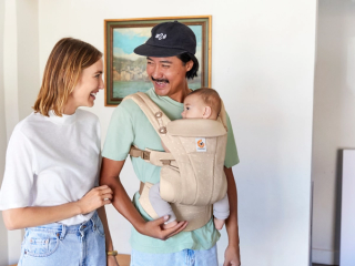 Dad wearing baby in ErgoBaby carrier whilst laughing with mum