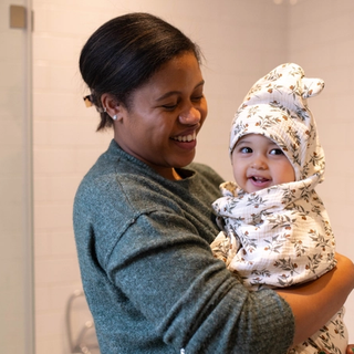 Mum holding baby wrapped up in a towel after a bath