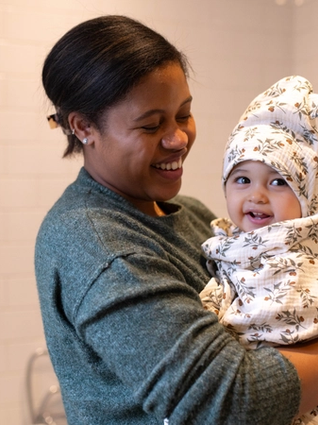 Mum holding baby wrapped up in a towel after a bath