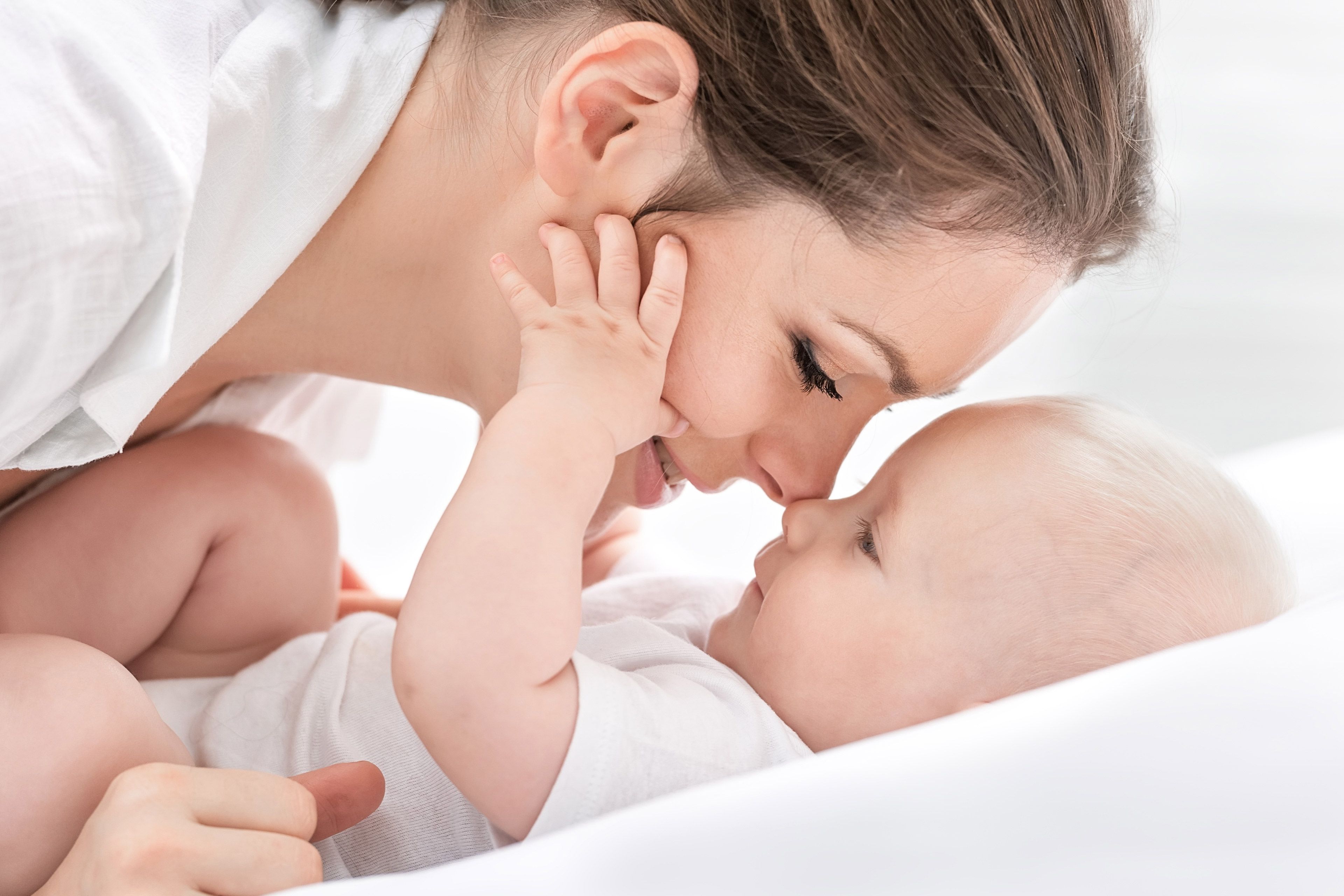 Ein zärtlicher Moment zwischen einer Frau und einem Baby, in dem die Frau sanft das Gesicht des Babys berührt und damit Gefühle der Liebe und Verbundenheit hervorruft.