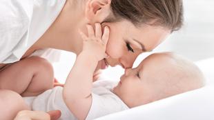 Ein zärtlicher Moment zwischen einer Frau und einem Baby, in dem die Frau sanft das Gesicht des Babys berührt und damit Gefühle der Liebe und Verbundenheit hervorruft.