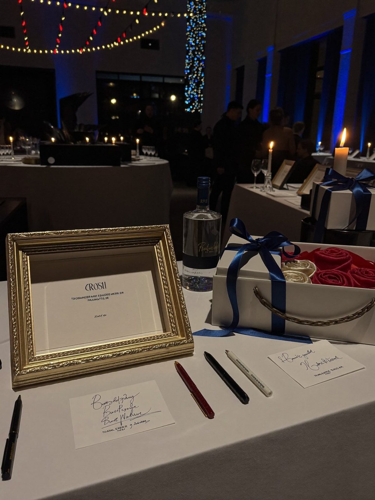 Silent auction items with bid sheets on a candlelit table