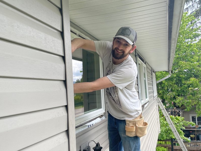 Drew Guthrie working the head flashing on a second-story dual-pane vinyl window install