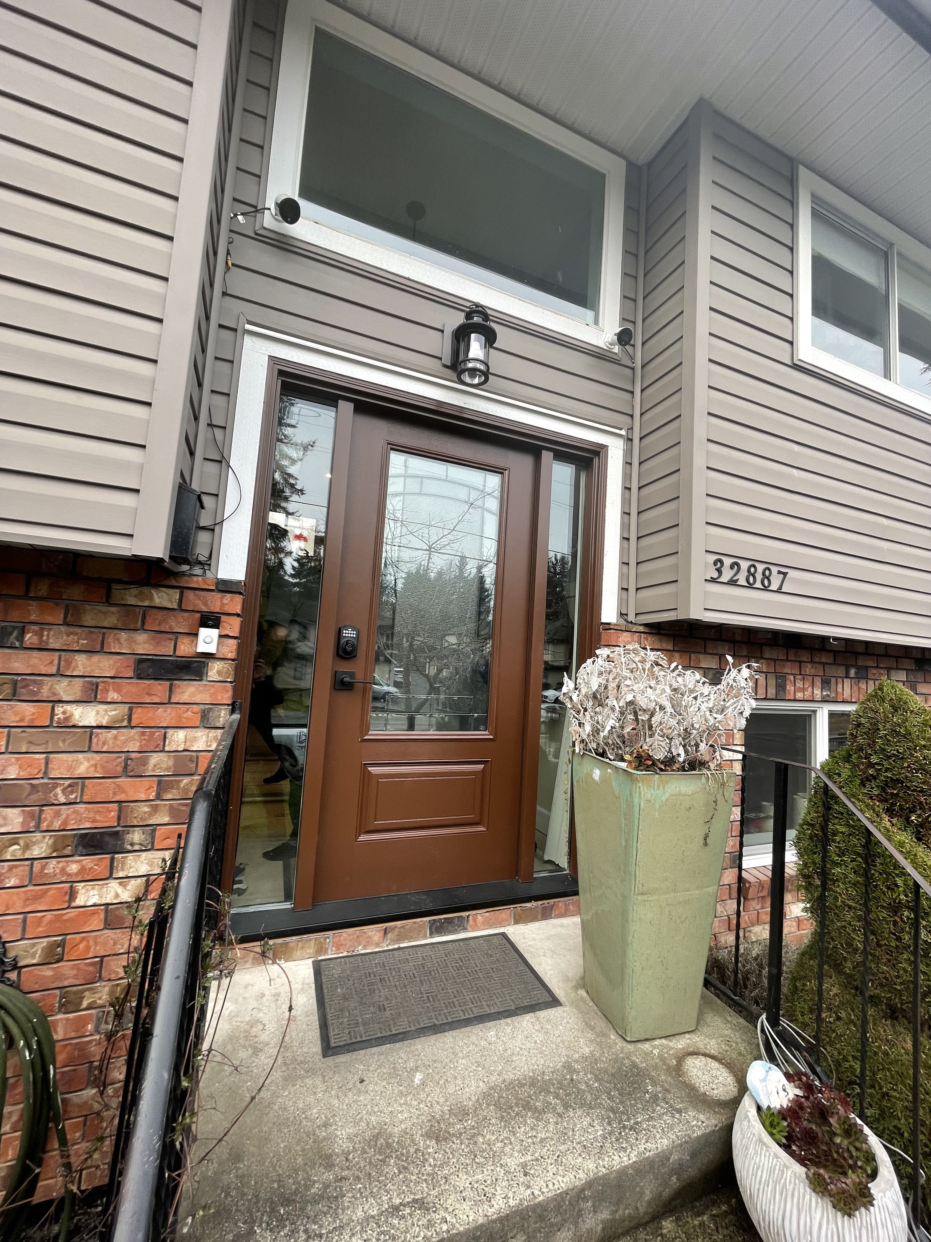 Fiberglass entry door installed on a two-story home with surround landscaping
