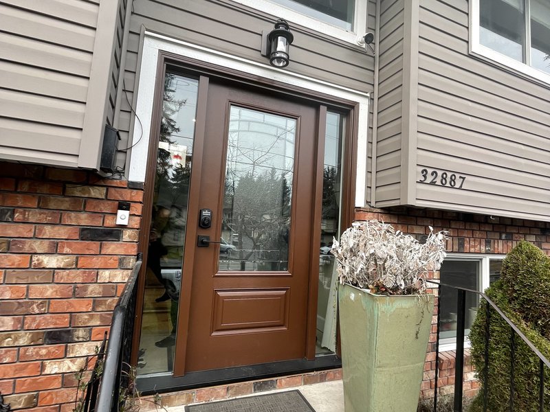 Fiberglass entry door installed on a two-story home with surround landscaping