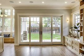 4-panel folding glass door fully open onto a backyard, viewed from a hardwood-floor great room