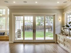 4-panel folding glass door fully open onto a backyard, viewed from a hardwood-floor great room