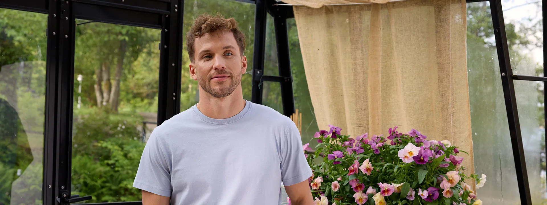 Man i ljusblå t-shirt med blommor i bakgrunden