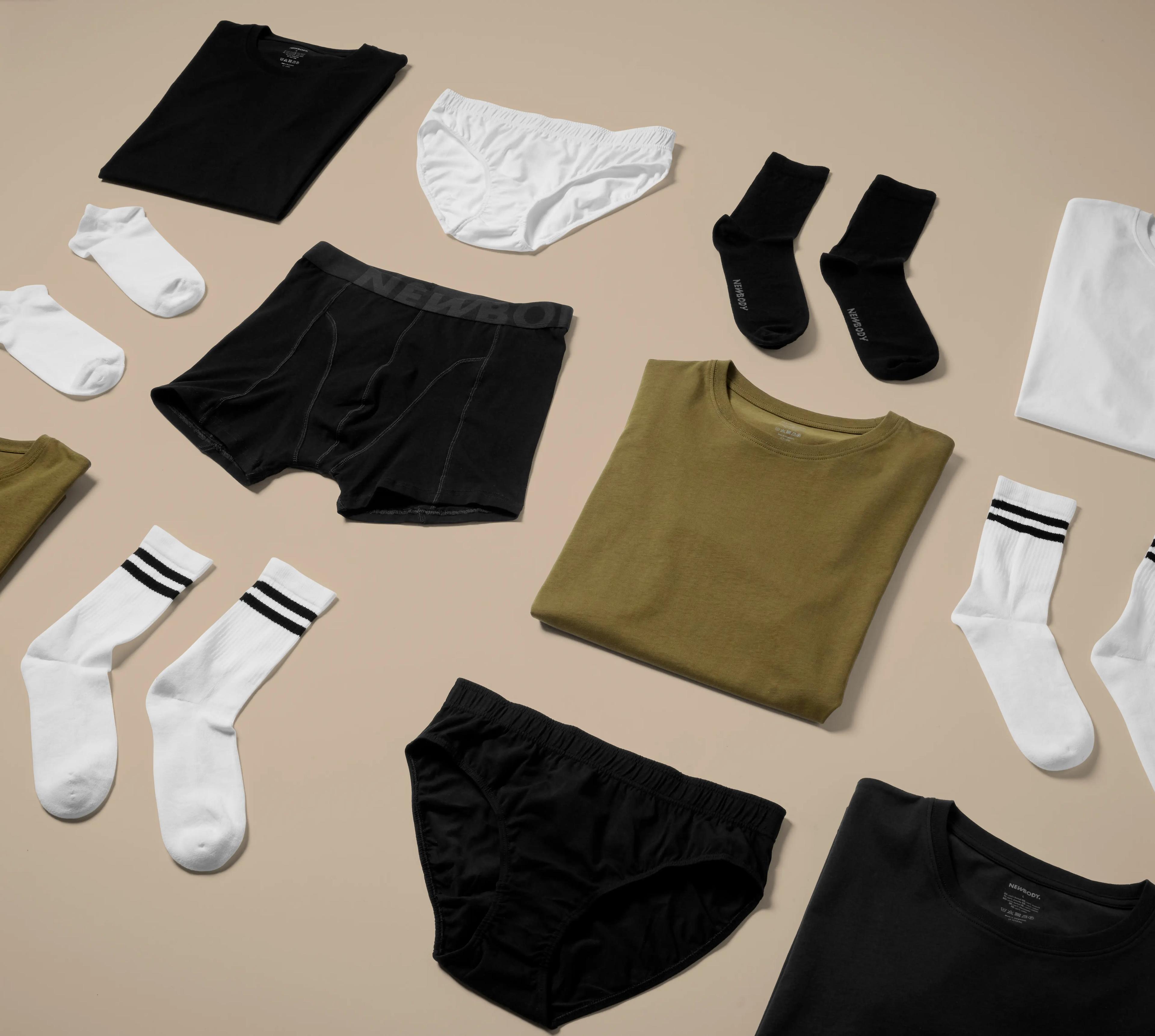 Olika plagg i neutrala färger, bland annat t-shirts, sockor och underkläder, snyggt upplagda på ett ljust underlag. Enkel design med fokus på basplagg för alla tillfällen.