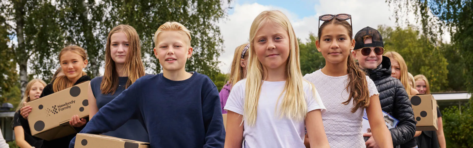 En skolklass på en skolgård med Newbody kartonger i famnen.