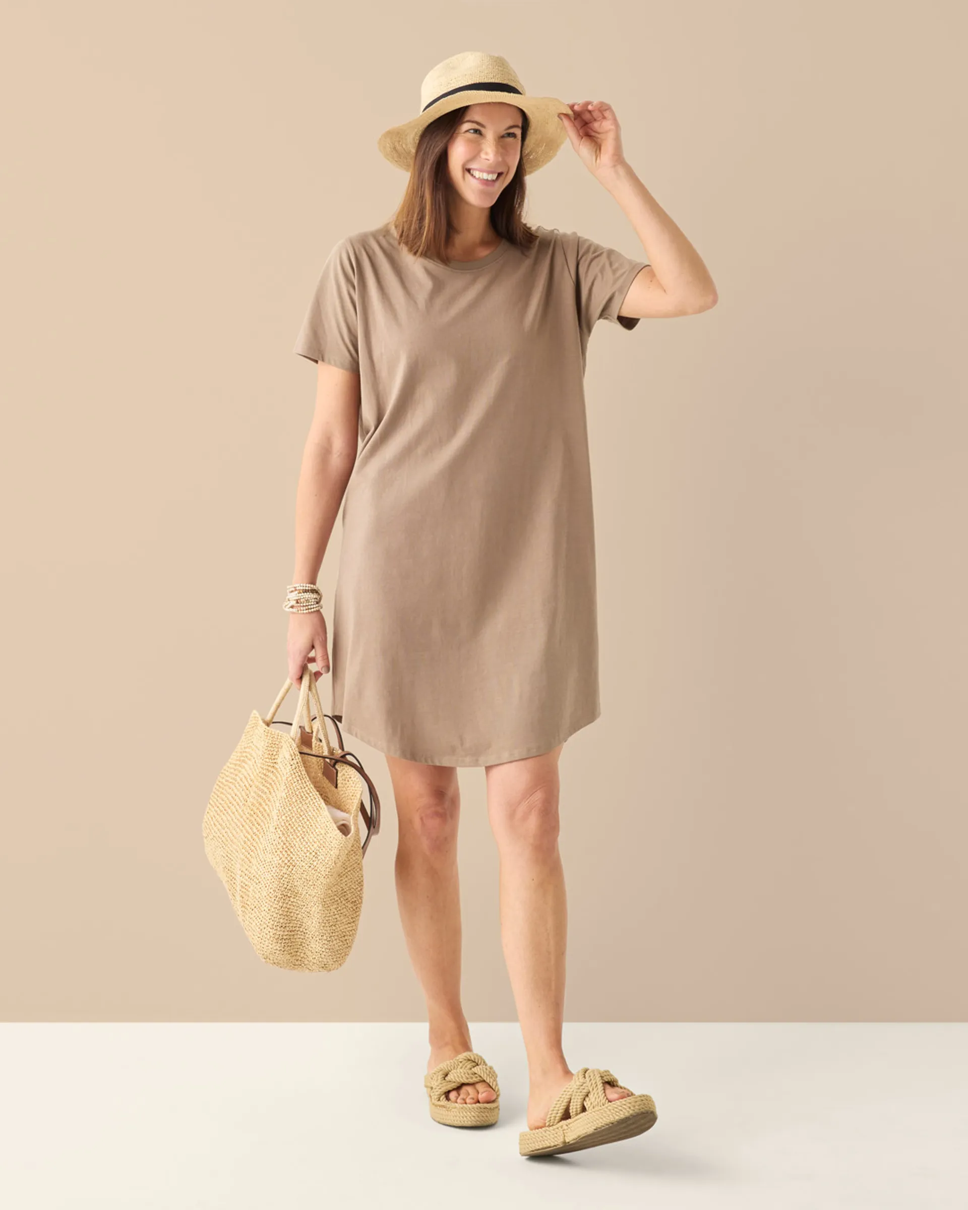 Mullvadsfärgad t-shirtklänning för dam, strandlook med solhatt och stråväska på modell.