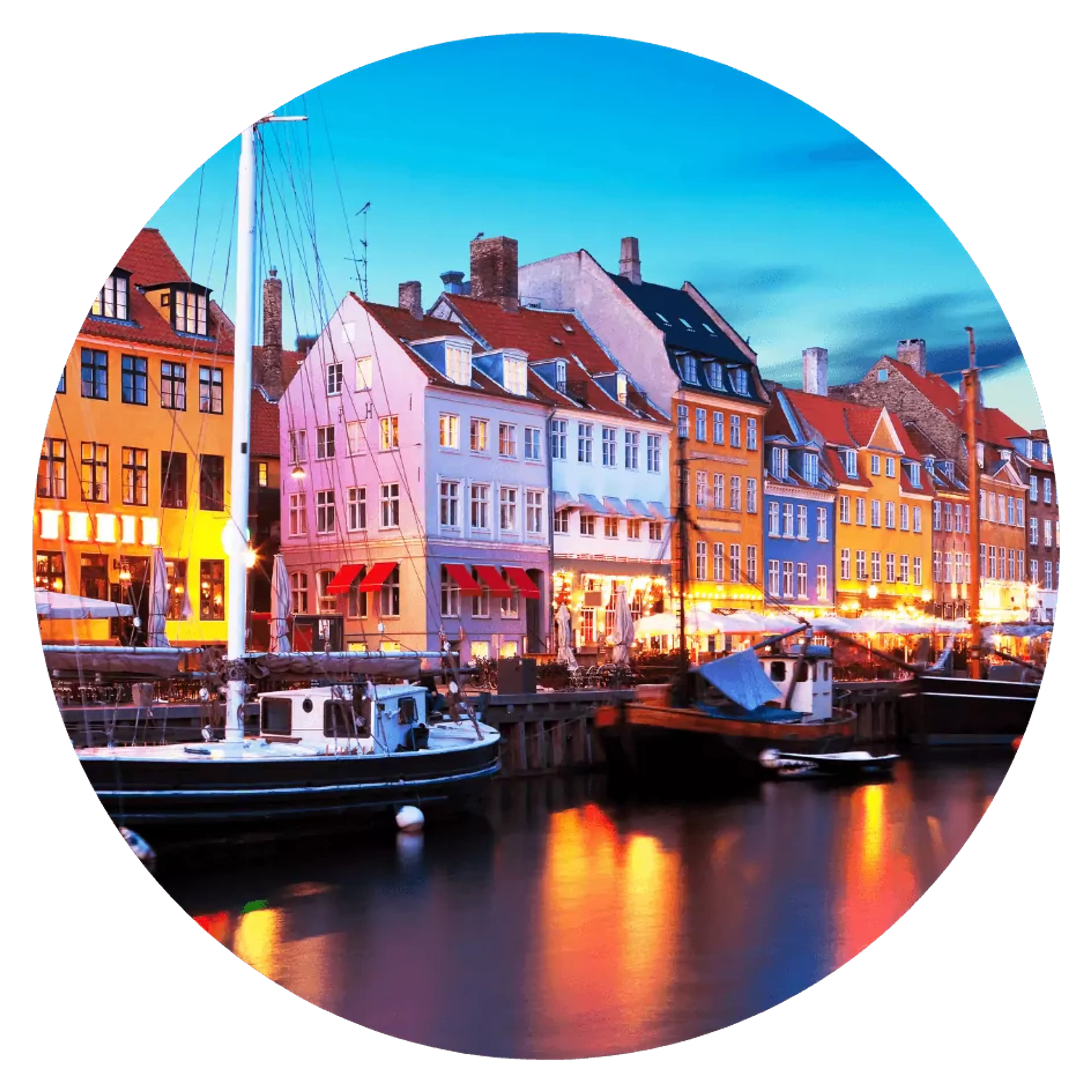 Färgglada hus reser sig längs kajen i Nyhavns hamn, där små båtar ligger förtöjda i vattnet. Ljuset från byggnaderna speglas mjukt i den stilla kanalen.