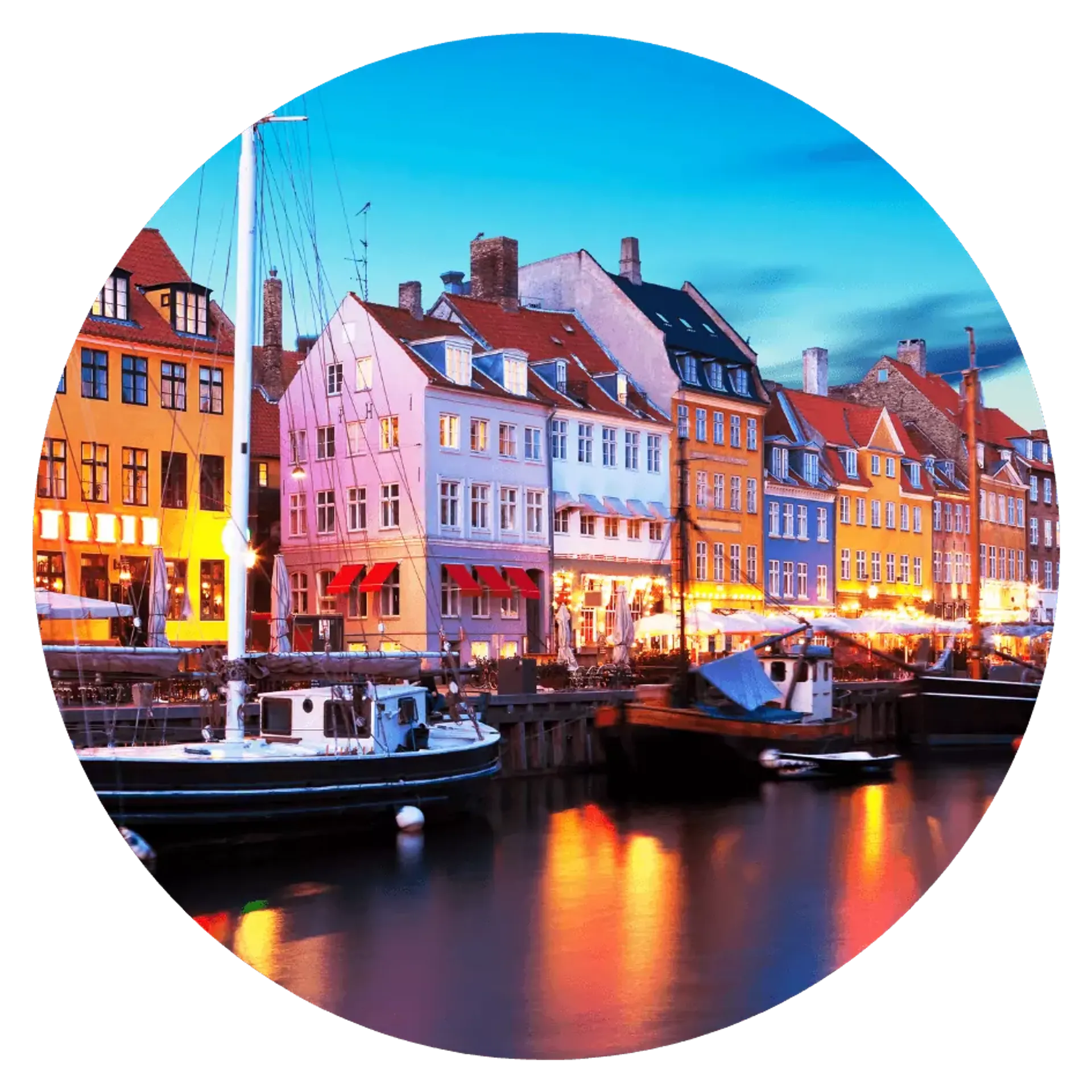 Färgglada hus reser sig längs kajen i Nyhavns hamn, där små båtar ligger förtöjda i vattnet. Ljuset från byggnaderna speglas mjukt i den stilla kanalen.