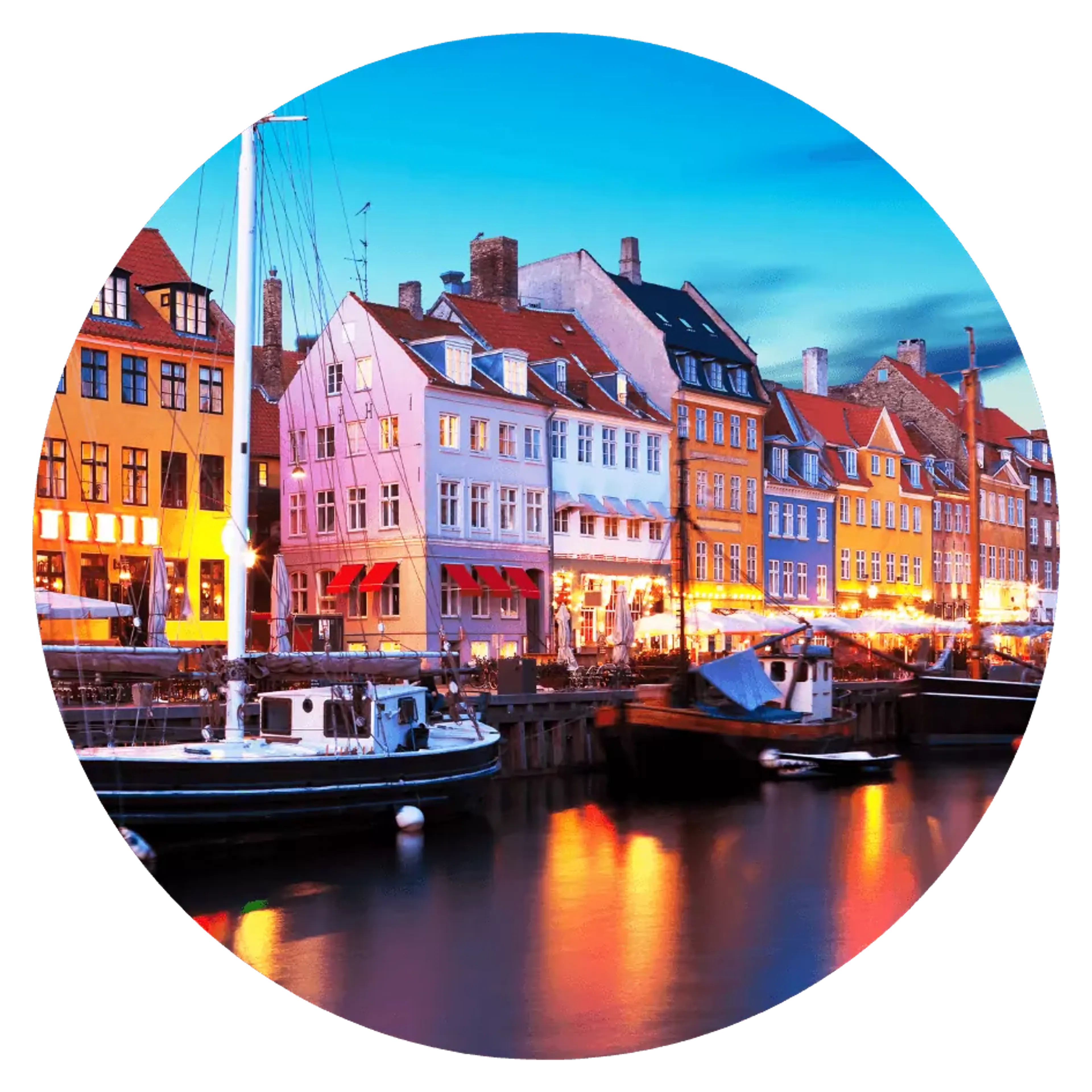 Färgglada hus reser sig längs kajen i Nyhavns hamn, där små båtar ligger förtöjda i vattnet. Ljuset från byggnaderna speglas mjukt i den stilla kanalen.