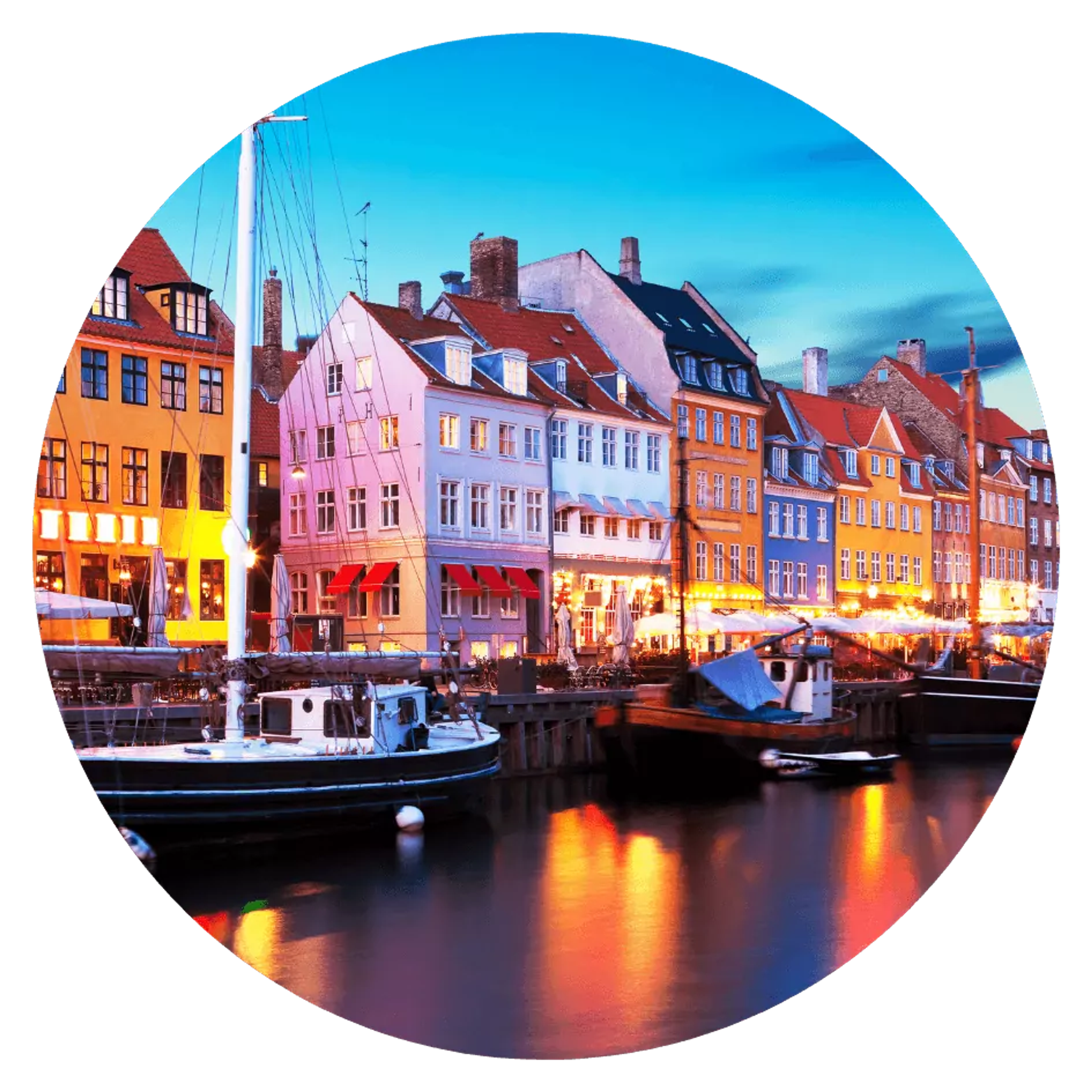 Färgglada hus reser sig längs kajen i Nyhavns hamn, där små båtar ligger förtöjda i vattnet. Ljuset från byggnaderna speglas mjukt i den stilla kanalen.