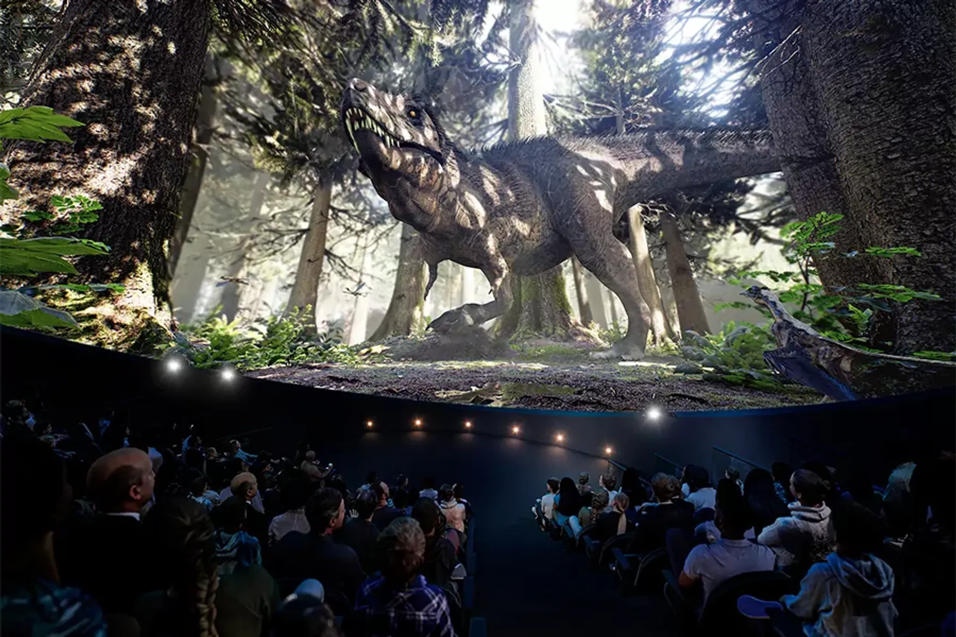 En stor grupp människor sitter tillsammans och tittar på en imponerande, realistisk dinosaurie i en kupolformad bioduk omgiven av skogsmiljö. Scenen skapar en känsla av att befinna sig mitt i en forntida natur.
