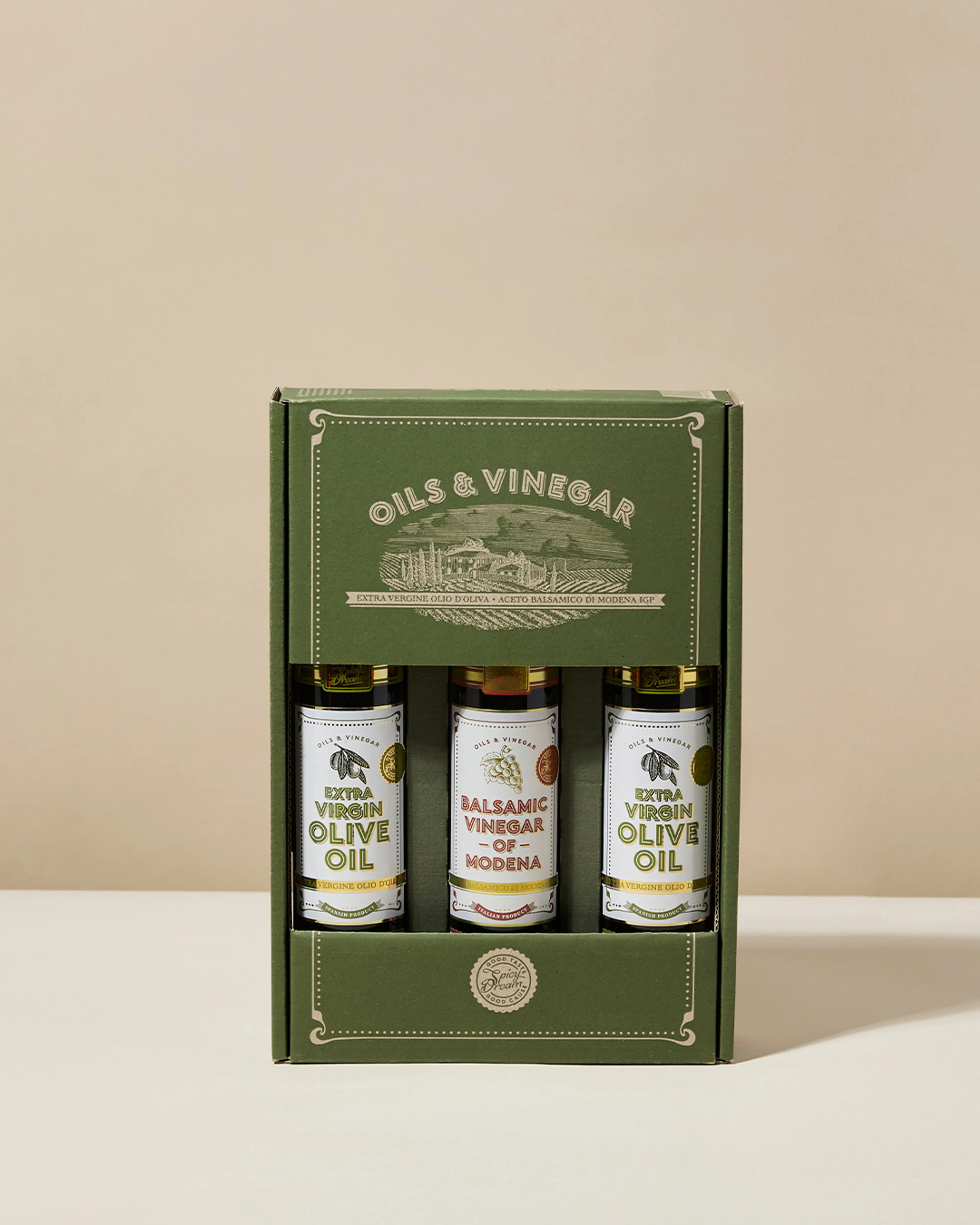 En kartong med tre flaskor innehållande extra virgin olivolja och balsamvinäger från Modena, med en grön och stilren förpackning. Flaskorna står prydligt uppradade och visar etiketterna tydligt.