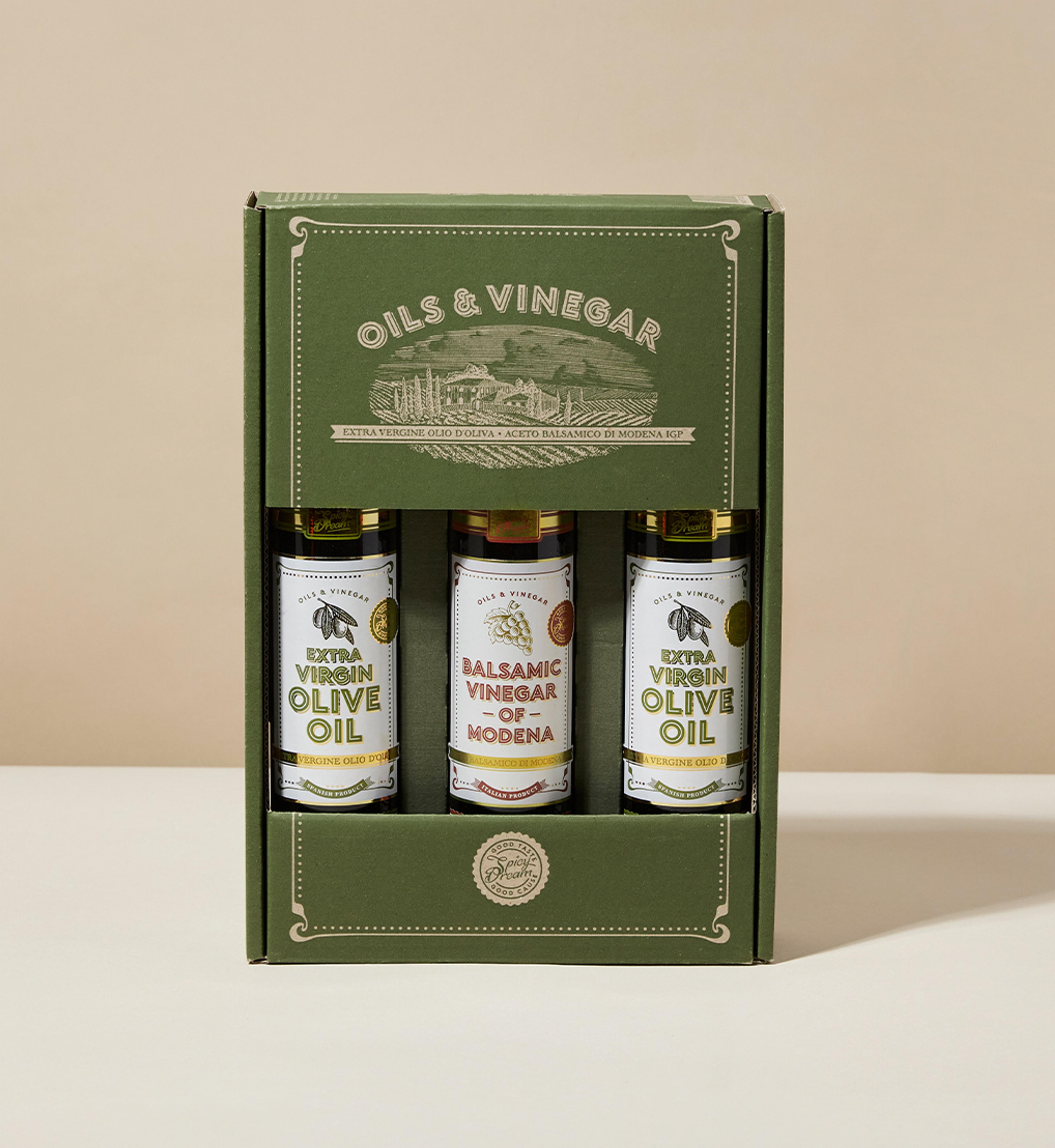 En kartong med tre flaskor innehållande extra virgin olivolja och balsamvinäger från Modena, med en grön och stilren förpackning. Flaskorna står prydligt uppradade och visar etiketterna tydligt.