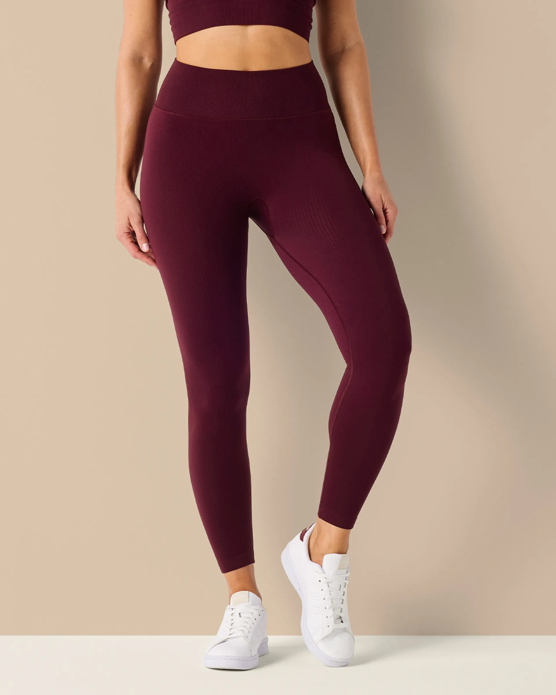 Mörkröda seamless tights med hög midja i mjukt, ribbat material, kombinerade med vita sneakers för en sportig look.