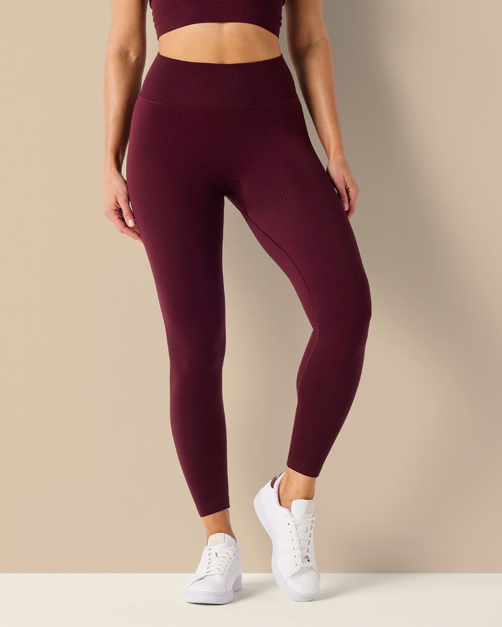 Mörkröda seamless tights med hög midja i mjukt, ribbat material, kombinerade med vita sneakers för en sportig look.