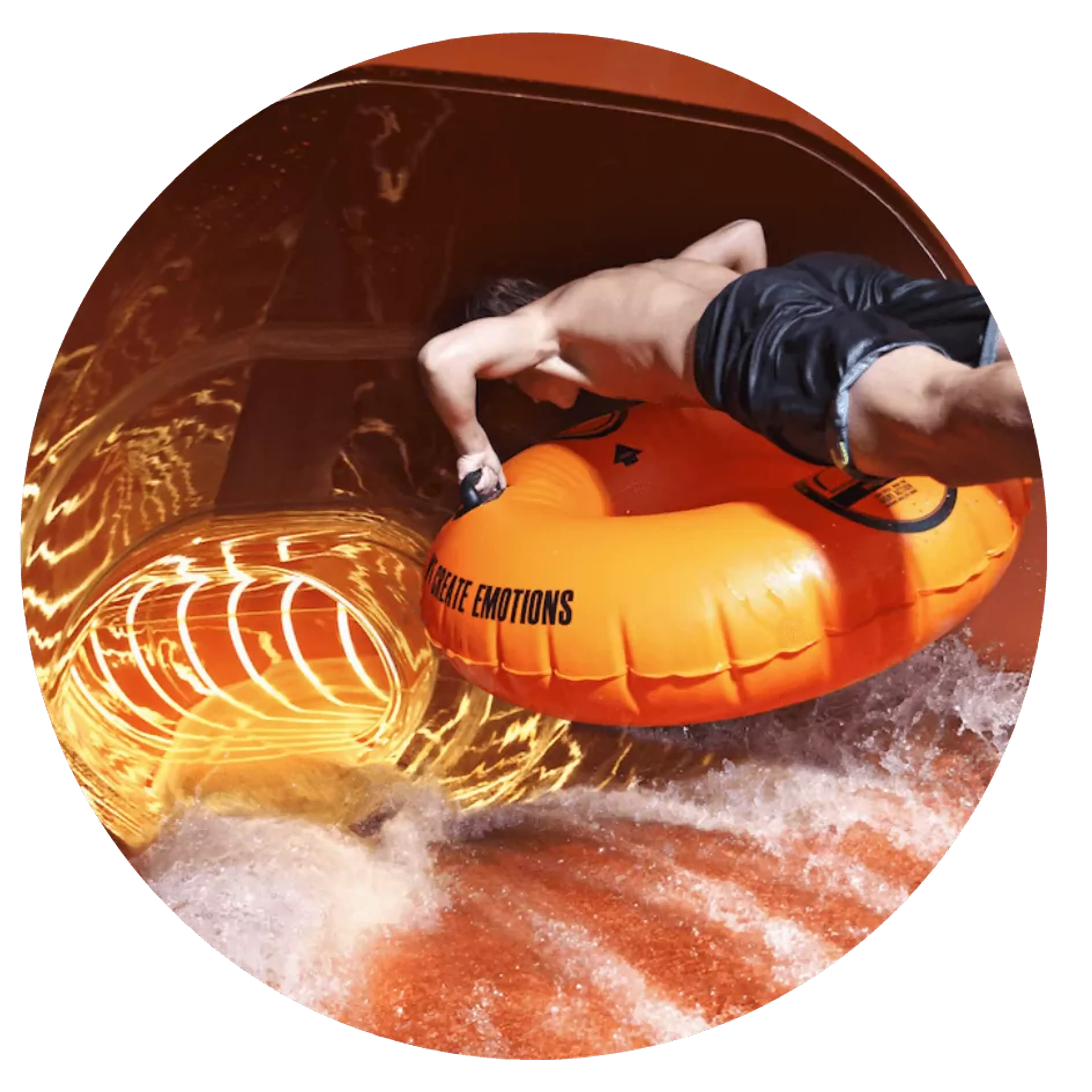 En person i badshorts åker på en orange uppblåsbar ring inne i en vattenrutschkana med orange och gula tonar. Vattnet skummar runt kanten på rutschkanan.