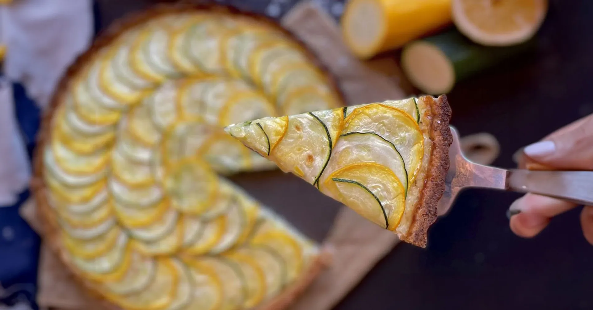 En paj dekorerad med tunna skivor av gul och grön zucchini