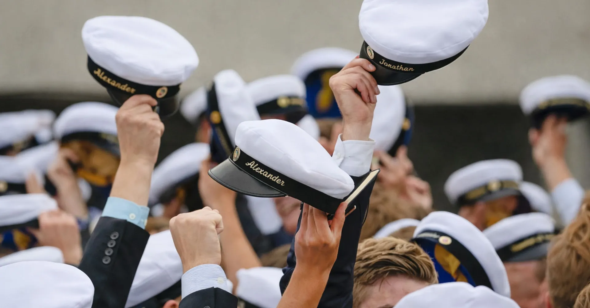 Händer som hissar studentmössor i vid ett studentfirande