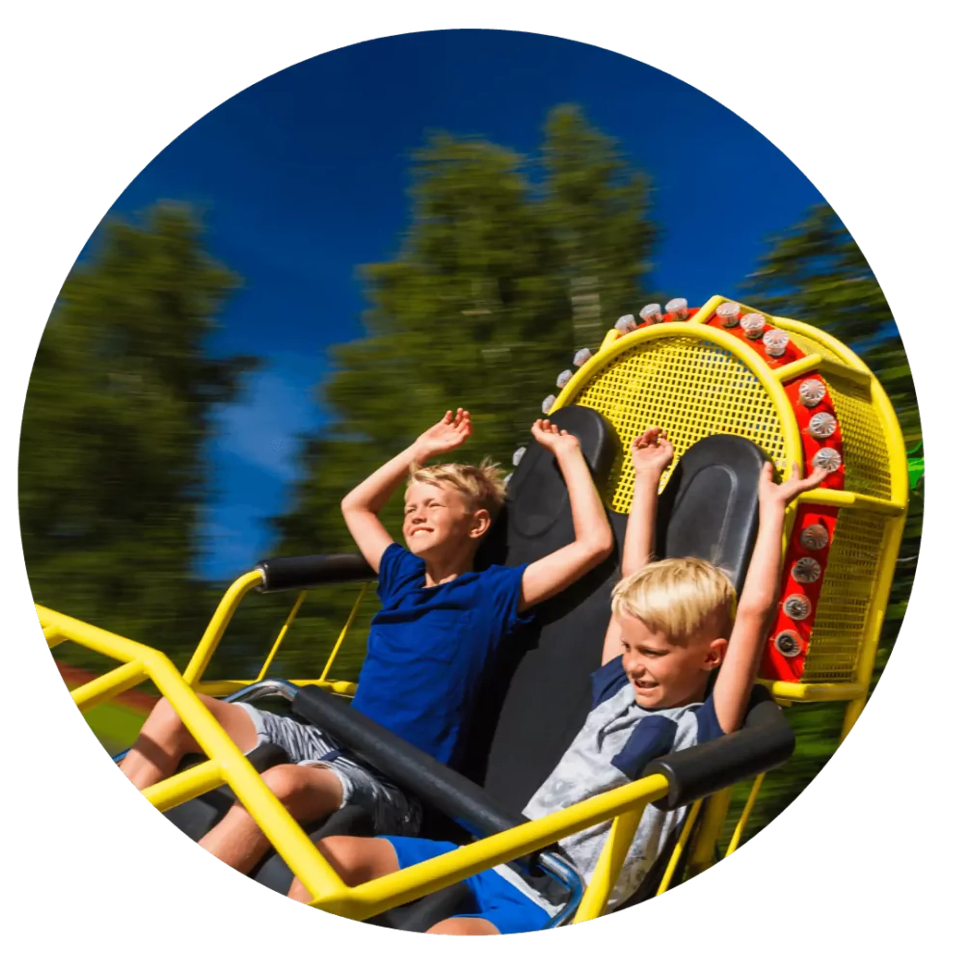 Två barn sitter i en gul och röd karusell med upphissade armar och blå himmel i bakgrunden. Trädens rörelseoskärpa visar att de åker snabbt.