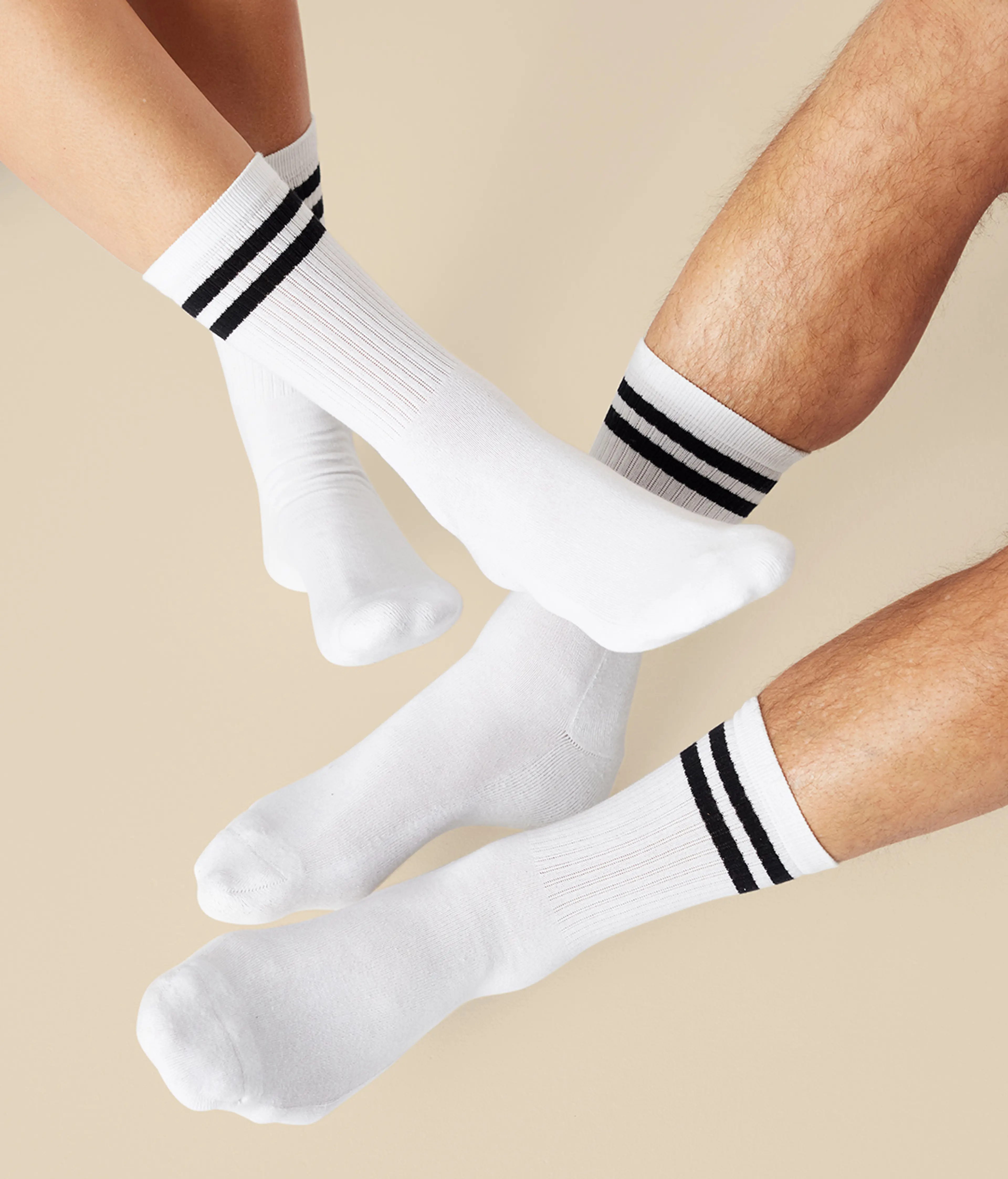 Vita sportstrumpor med två svarta ränder vid skaftet, visade på både dam- och herrben. En enkel och klassisk design för både vardag och aktivitet.