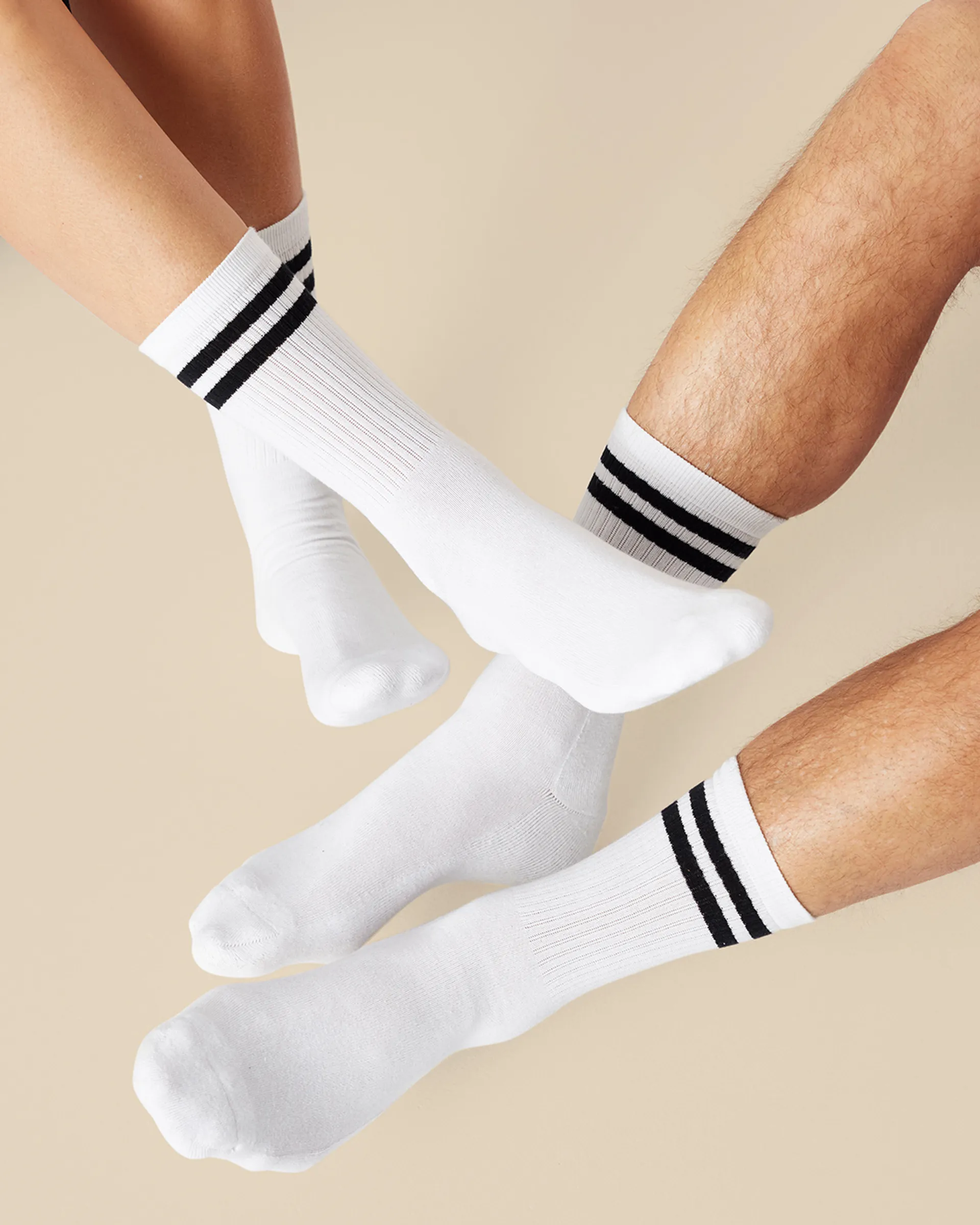 Vita sportstrumpor med två svarta ränder vid skaftet, visade på både dam- och herrben. En enkel och klassisk design för både vardag och aktivitet.