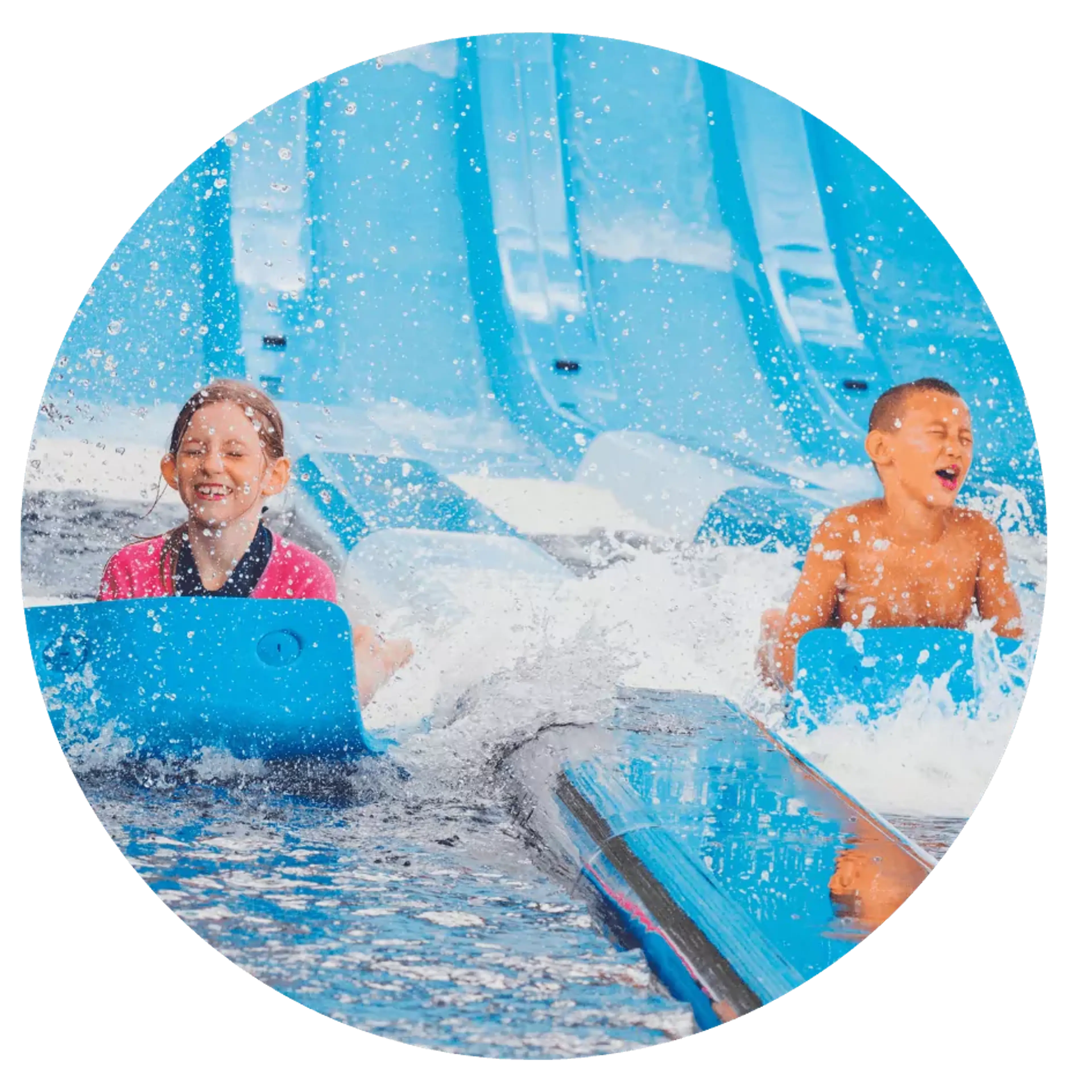 Två barn åker bredvid varandra på blå vattenrutschkanor och plaskar i vattnet. Bakgrunden visar flera ljusblå rutschkanor vid en vattenpark.