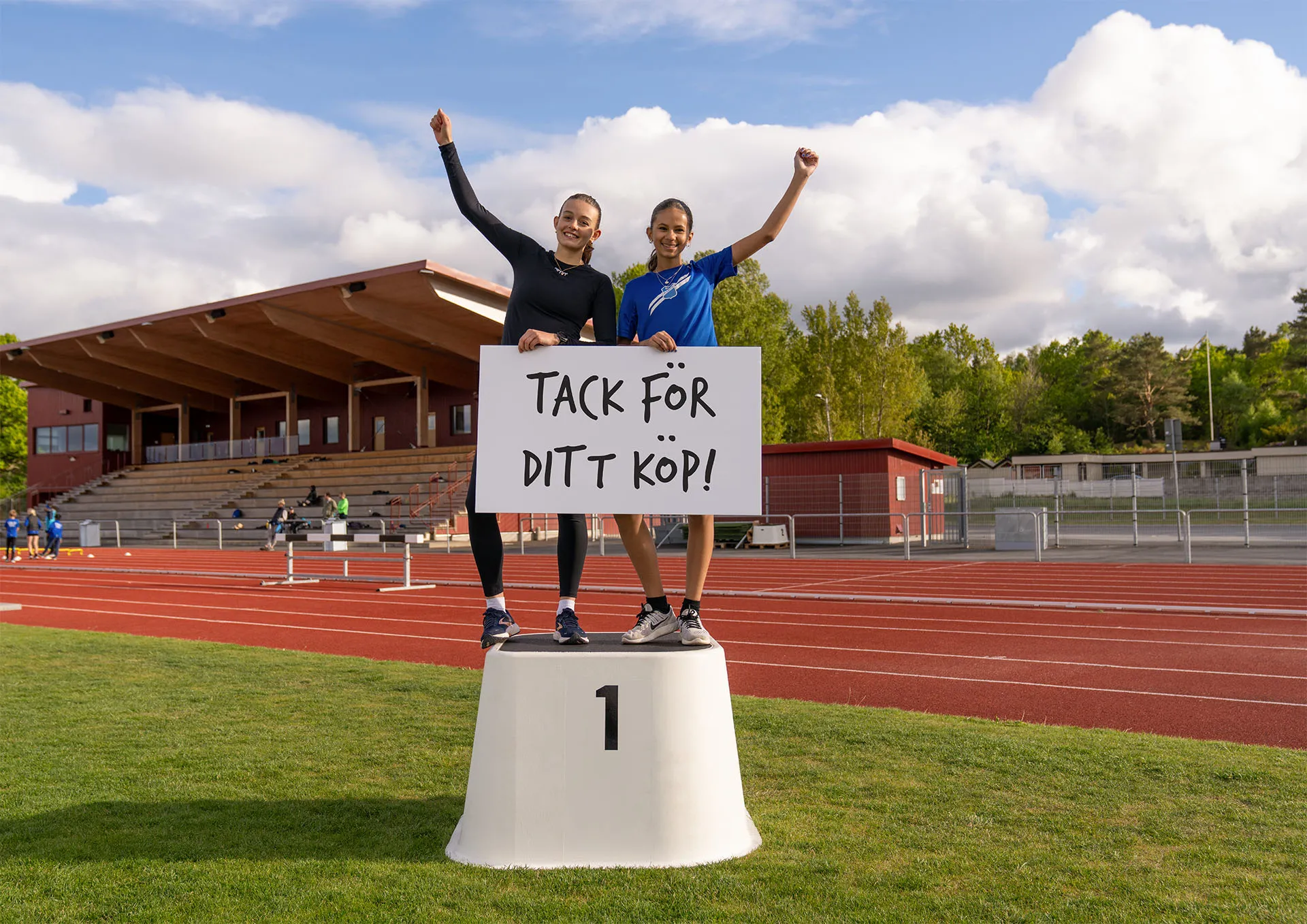 två tjejer på en prispall med en skylt i händerna där det står "Tack för ditt köp!"
