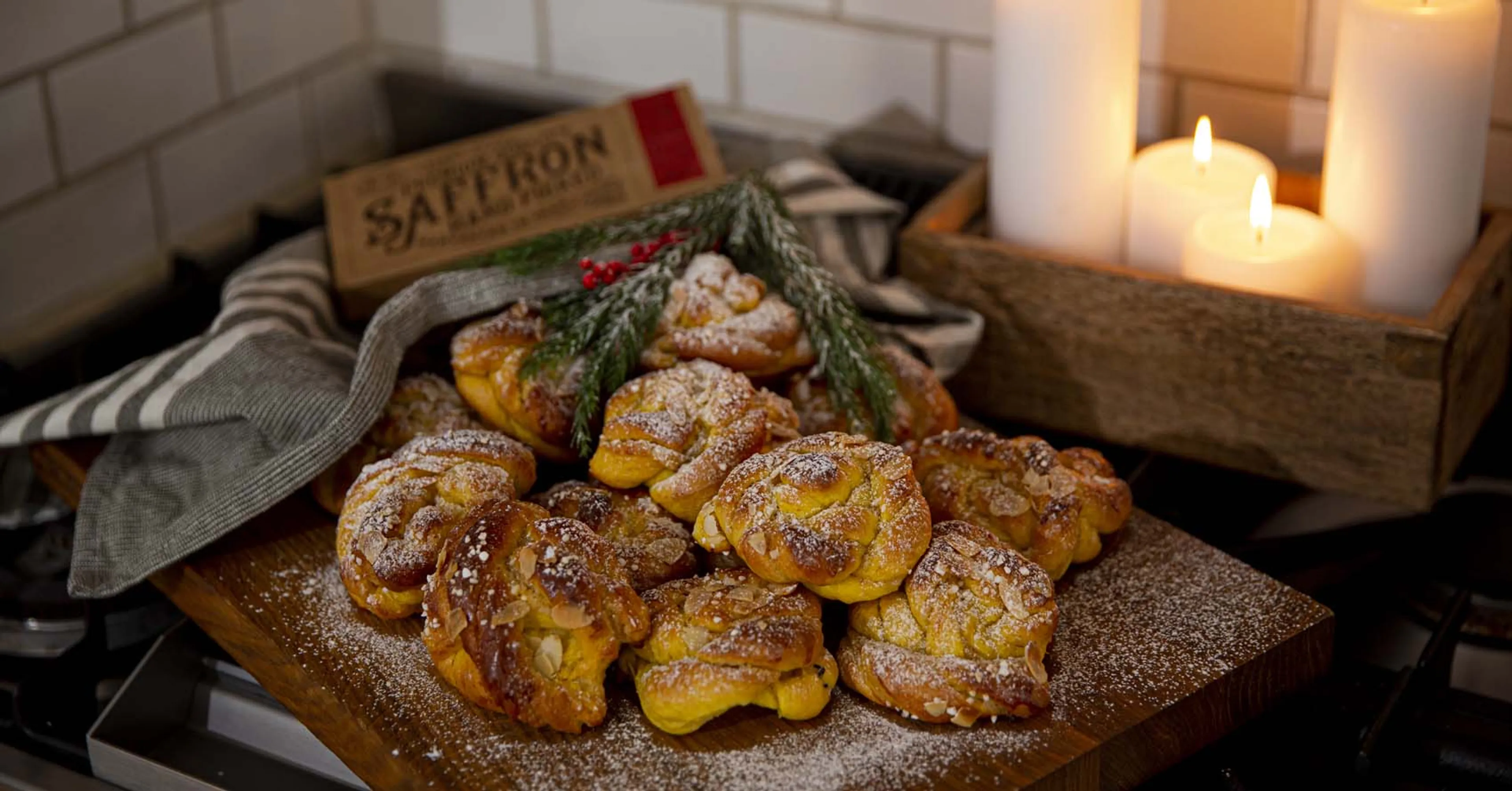 Stämningsfull julbild av saffransbullar på ett fat med tända ljus i bakgrunden