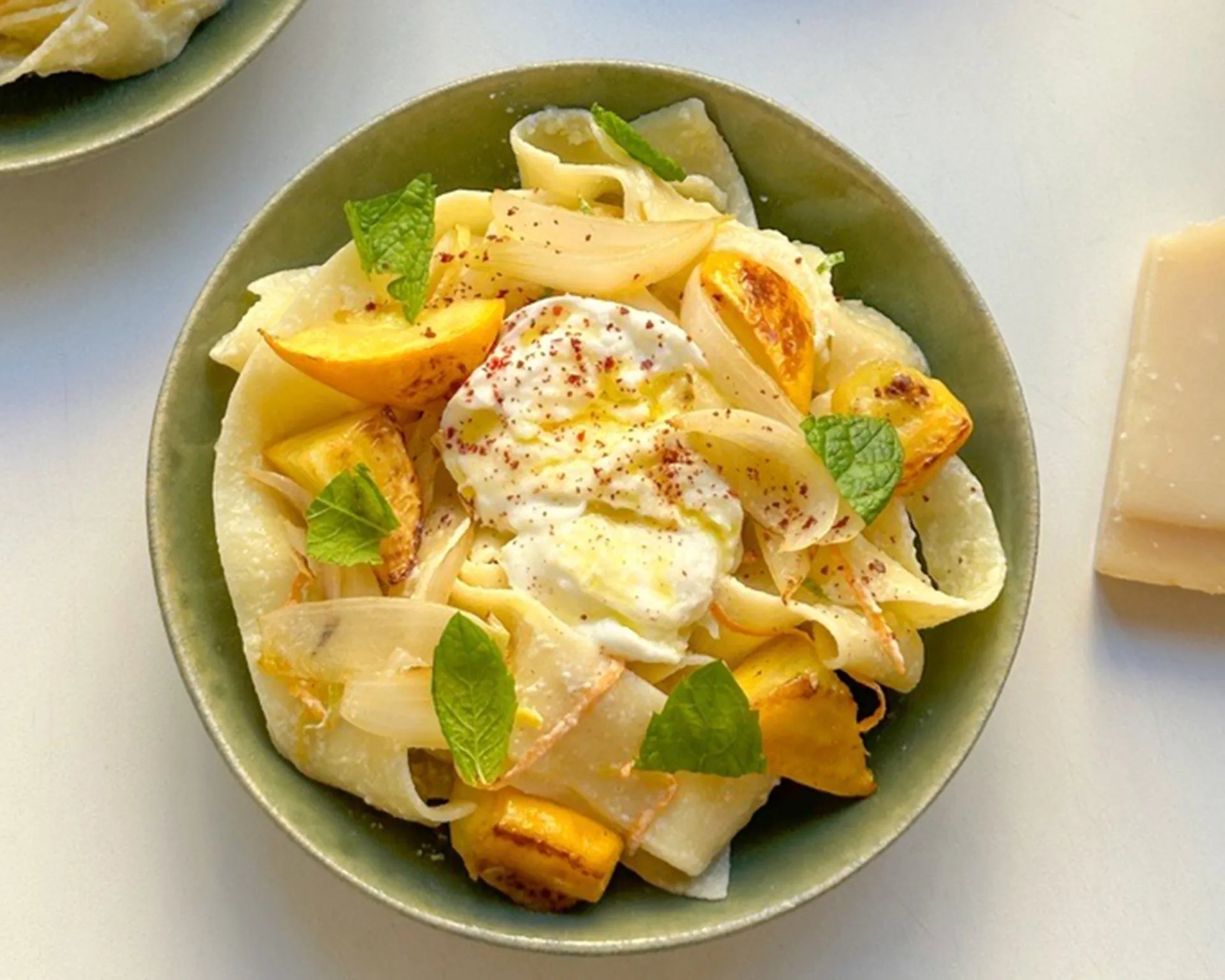 Gräddig pappardelle med citronbitar, karamelliserad lök och färska myntablad. En fräsch komposition med en touch av kryddor.