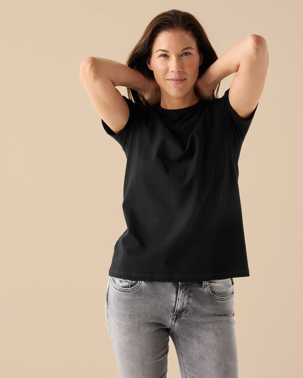 Svart t-shirt dam, rund hals, kombinerad med ljusgrå jeans för vardagslook.