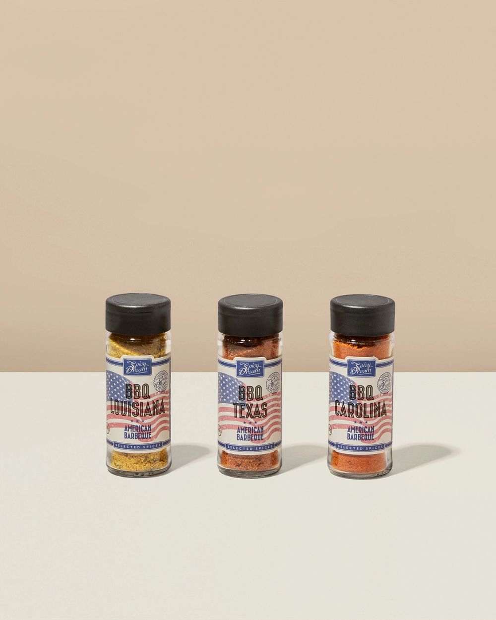 Tre kryddburkar med olika amerikanska BBQ-smaker: Louisiana, Texas och Carolina, med etiketter prydda av en amerikansk flagga.